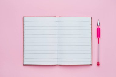 Boş sayfa ve pembe kalemile açık bir not defterinin üst görünümü. Okul konseptine geri dön. 