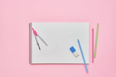 Pastel pembe zemin üzerinde kalemler ile Spiral not defteri. Okul konseptine geri dönelim. Kopya alanı, üst görünüm.