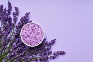 Lavanta Spa. Mor arka planda kase de lavanta çiçekleri ve banyo tuzu. Kopya alanı, üst görünüm. Spa konsepti.