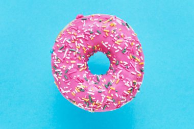 Serpiştirilmiş Pembe Donut. Mavi arka plan üzerine sırlı serpiştirilmiş çörek. Üst görünüm, kopyalama alanı.