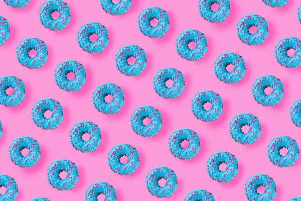 Pattern of a blue donuts on a bright pink background. Flat lay