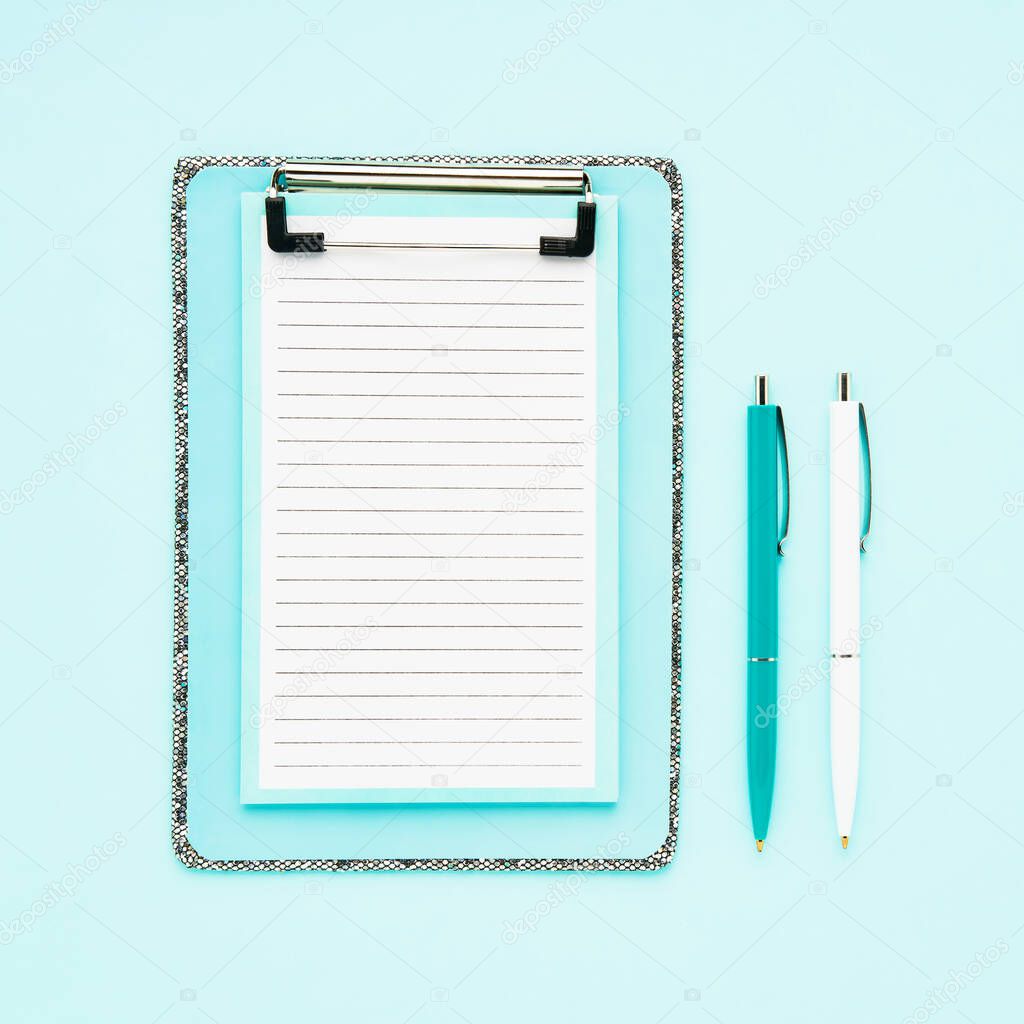 Blank clipboard mockup and ballpoint pens on light blue color background. Top view, copy space for text. Back to school, deadline, morning concept.