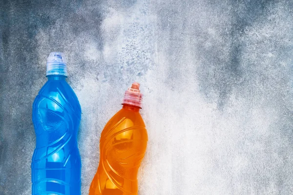 Blue and orange isotonic energy drink on gray-blue background. Sport concept. Top view, copy space for text, selective focus