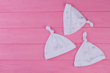 Şapka yeni doğan, en iyi görünüm için kümesi. Üç pamuk düğüm şapka pembe ahşap arka plan, kopya alanı üzerinde yeni doğan kız için. Çocuklar için aksesuarlar.