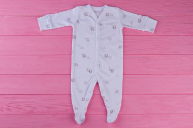 Yeni doğan çocuk için dipleri giyerlerdi. Beyaz uzun kollu tulum fil için bebek kız, pembe ahşap arka plan yazdırma. Kız bebek için güzel romper .