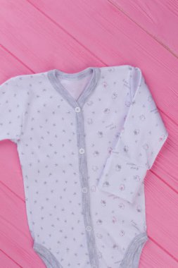 Bebekler için yeni yazdırılan giyerlerdi. Renkli ahşap arka plan üzerinde bebek için organik tek parça takım elbise. Çocuklar için kaliteli hazır giyim.