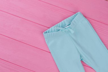 Bebek mavi şık pantolonlar. Yumuşak giysilerinle ahşap arka plan, kopya alanı üzerinde çocuklar için. Childs'ın için marka kıyafet.