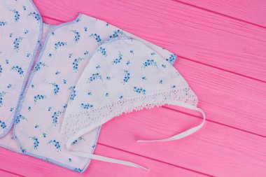 Organik Bebek giyim. Kısa bebekler fanila düğmeleri ve pembe ahşap arka plan, üstten görünüm şapka olmadan.