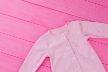 Bebek kız giysileri pembe ahşap üzerine. Üstten görünüm. Yeni doğan gömlek kırpılmış görüntü.