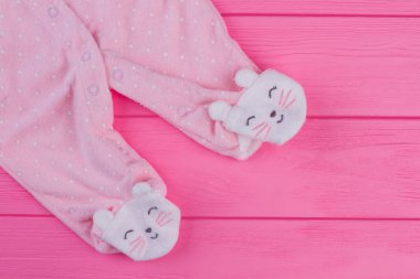 Ahşap üzerine pembe ayaklı bebek pijama bacakları. Üstten görünüm. Pembe bir arka plan.