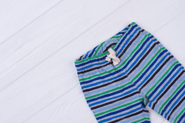 Şeritli bebek pantolon. Beyaz tahta arka plan.