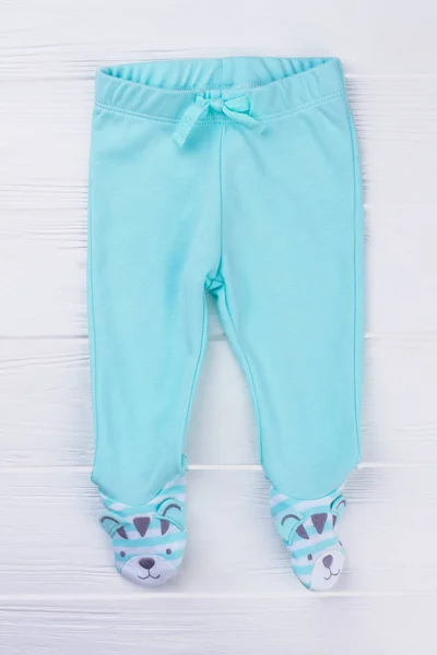 Blue footed pants for kids. White wood background.