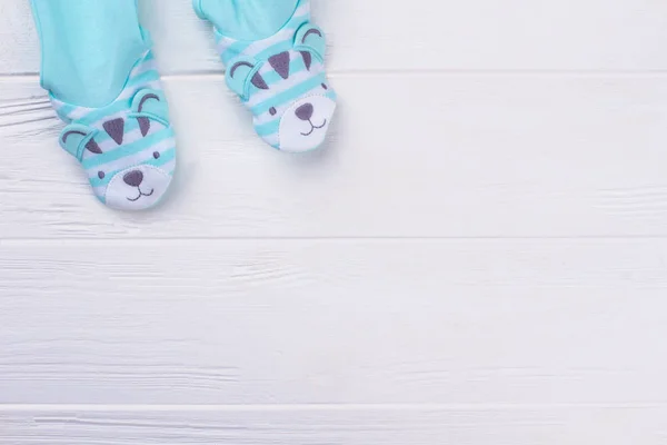 Footed pajamas legs with copyspace. White wooden background.
