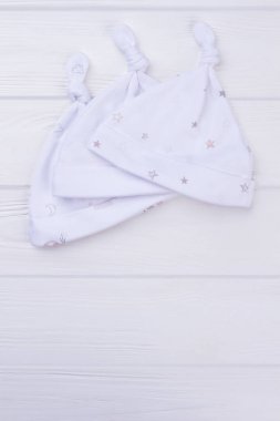 Üç beyaz bebek yenidoğan şapka. Beyaz tahta arka plan.