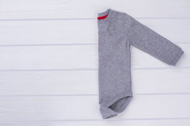 Bebek onesie beyaz tahtaya katlanmış. Beyaz ahşap zemin.