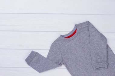 Gri onesie çocuklar için. Üstten görünüm. Beyaz tahta arka plan.