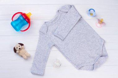Bebek essentials aranjman. Giyim ve oyuncak. Onesie, peluş köpek, şişe ve ahşap üzerine üç emzik.