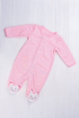 Ahşap üzerine pembe ayaklı bebek kız pijama. Üstten görünüm. Beyaz tahta arka plan.