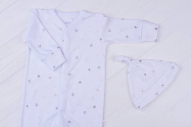Bebek pijama ve düğüm şapka. Üstten görünüm. Beyaz tahta arka plan.