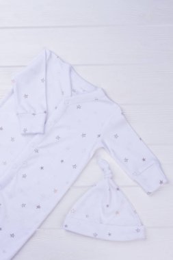 Beyaz bebek şapka ahşap üzerine pijama ve düğüm. Yıldız ile baskılı bebek pijama takım.