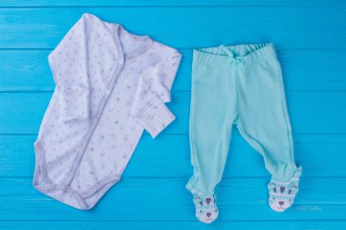 Bebek pijama onesie pijama ve ayaklı pantolon. Komik ayaklı ayı pantolon mavi ahşap üzerine dekore edilmiştir..