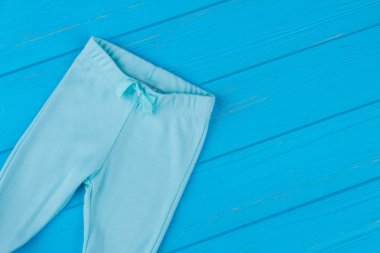 Mavi pantolon ahşap üzerine eğildi. Çocuklar için rahat yumuşak pamuk pantolon. Mavi arka plan.