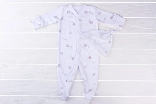 Vit Footed Baby Pyjamas Och Knut Hatt Vit Trä Skrivbord — Stockfoto