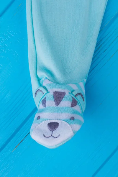 Adorable footed baby pajama foot with bear. Blue wood background.