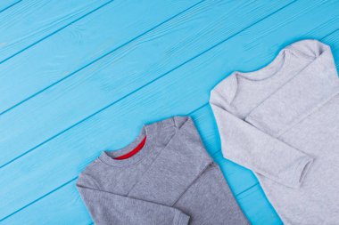 İki onesie creepers ve ahşap üzerine boşaltmak. Çocuklar için pamuklu giysiler. Mavi arka plan.