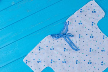 Bebek tshirt ile düğüm. Üstten görünüm. Mavi ahşap Resepsiyon arka plan.