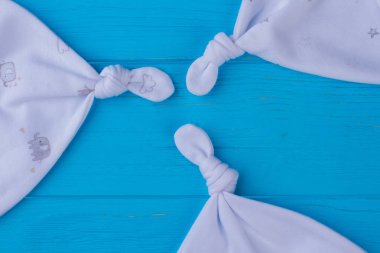 Beyaz bebek düğüm şapkalar mavi toplamak. Yakın çekim. Ahşap Danışma backgorund.