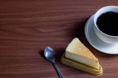 Koyu ahşap bir masada sıcak kahveli cheesecake ve kopyalama alanı