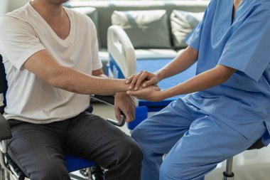 Asyalı bir erkek hasta hastane yatağında yatıyor ve bir doktordan iyi bakımı alıyor. Doktor, erkek hastaya sağlık teşhisi konusunda tavsiye veriyor.