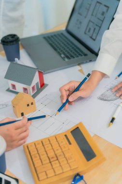 Mimarlık ve İnşaat Konseptleri - Dizüstü bilgisayarlı bir grup mimar, bina tasarımını planlamak için çatıda planlarla buluşuyor.