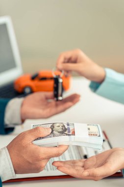 Erkek bir araba satıcısı araba alan ya da kiralayan bir müşteriye anahtarları teslim ediyor. Araba kiracılarına kredi ve araba sigortası için danışmanlık yapın