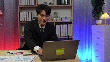 Asyalı iş adamı fazla mesai yapıyor ve heyecanlanıyor. Ofiste iyi bir işle yapılan iş kutlaması. Sigorta ve pazarlama işi.