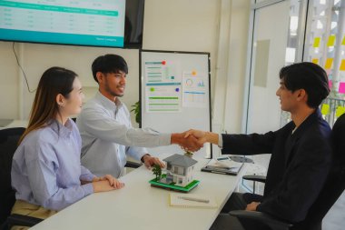 Kağıt işleri ve gülümseme ile işi bitiriyorum. Bir çift el sıkışır ve dairelerinin başarılı satışından dolayı emlakçıya teşekkür eder, sonra anlaşmayı tamamlar ve yeni evlerinin satın alınmasını kutlar..