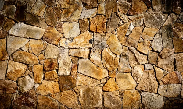 Texture of a varnished stone garden wall, with orange and yellow tones - Natural lighting - Construction material