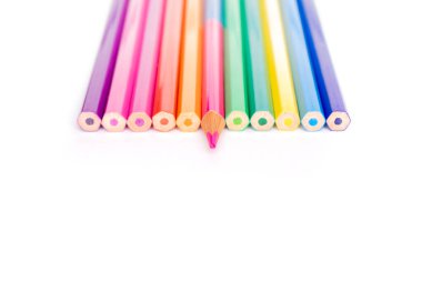 Dikey fotoğrafın üzerine dizilmiş renkli kalemler var. Beyaz bir arkaplanda