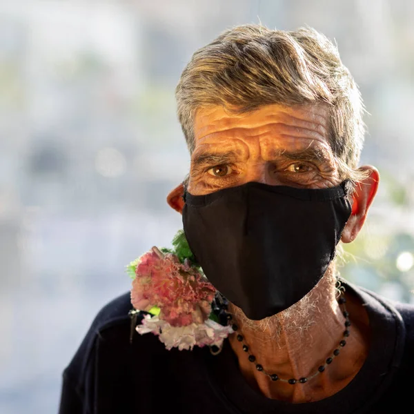 man with rude personality with mask and hanging flower - humble man - portuguese native man - selective focus