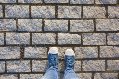 Granit kaldırım taşı kaldırım arka plan üzerinde spor ayakkabı ayaklarda