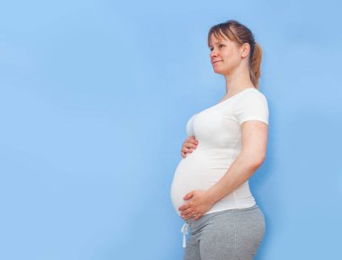 Mavi duvarda hamile bir kadın var.