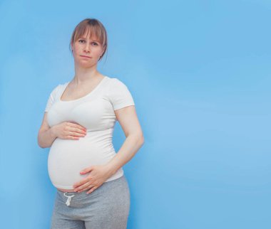 Mavi duvarda hamile bir kadın var.