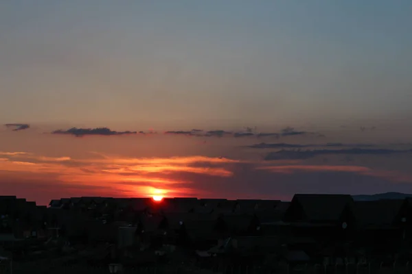在有橙色天空和云彩的房子后面 夕阳西下 — 图库照片