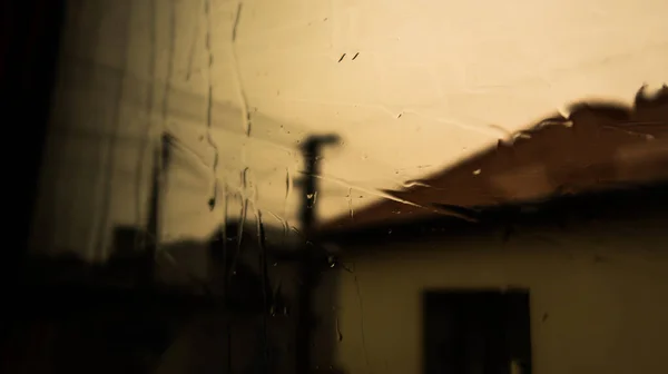 窗户上的水雨落在窗玻璃上 通过玻璃和雨给树和大自然蒙上阴影 房屋建造的阴影 — 图库照片
