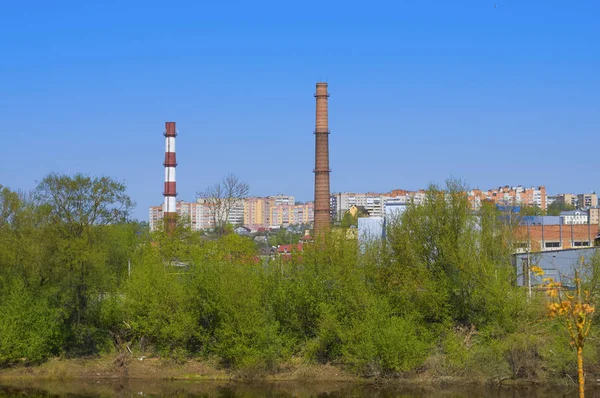 Industriële landschap met fabriek leidingen tegen de blauwe hemel en — Stockfoto