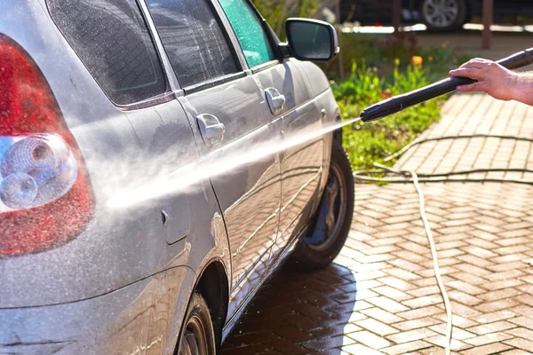 Washing a dirty car with a strong water jet from the hose of a special washing machine