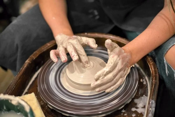 Hands in clay on the background of a rotating potter's wheel