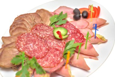 Et dilimleri ile Yeşiller, zeytin ve beyaz bir tabakta sebze yakın çekim izole