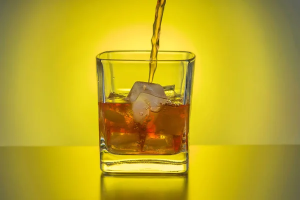 Виски Наливают Прозрачное Стекло Льдом Фоне Желтого Источника Света — стоковое фото